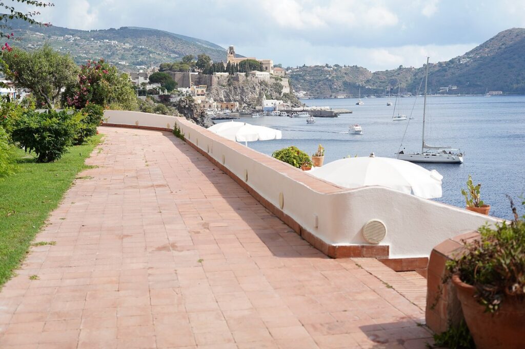 Lipari con bambini: attività per tutta la famiglia — The castle and harbour of Lipari seen across the bay from the seafront terrace of the Hotel Carasco, in the Aeolian Islands, Sicily, Italy.