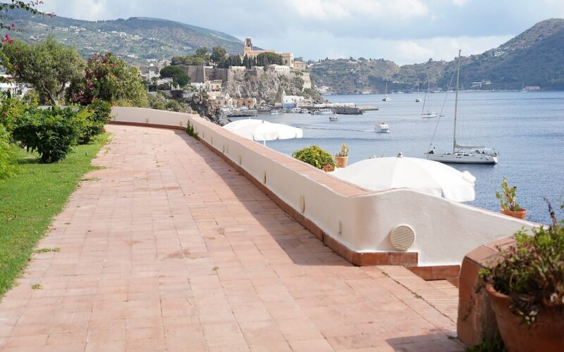 Lipari con bambini: attività per tutta la famiglia — The castle and harbour of Lipari seen across the bay from the seafront terrace of the Hotel Carasco, in the Aeolian Islands, Sicily, Italy.